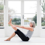 Senior women doing yoga in her brightly lit living room